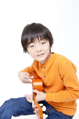 Ukulele çalan Asyalı çocuk.