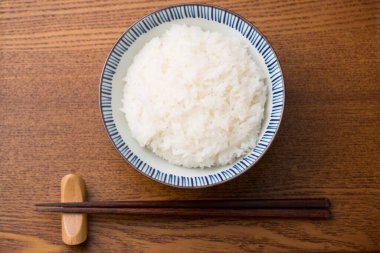 Ahşap zemin üzerinde buğulanmış Japon pirinci kasesi