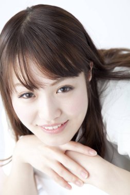 Beyaz arka planda gülümseyen Asyalı genç kadın.