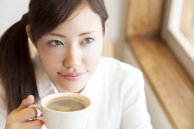 Genç güzel Asyalı kadın kahve içme