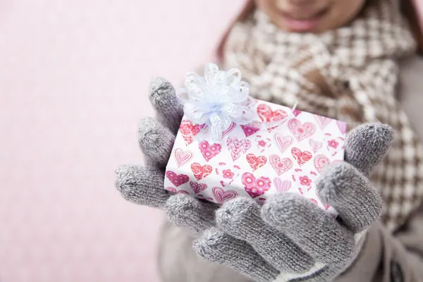 young woman in winter gloves holding gift box