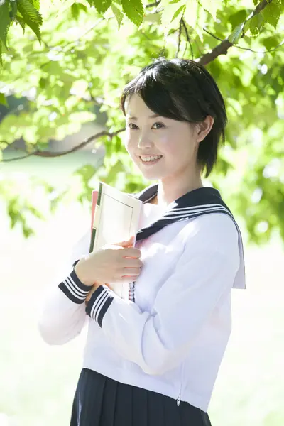 アジアの女の子の肖像画 学校の制服を着て屋外で本を保持する — ストック写真