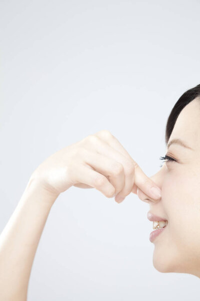 young asian  woman smelling something, studio shot