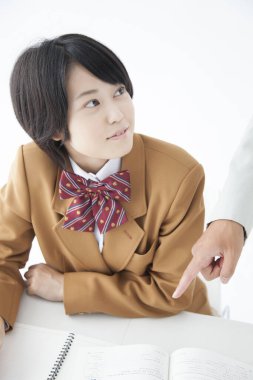 Genç Asyalı kız okul üniforması giyiyor. Sınıfta öğretmenle ders çalışıyor.