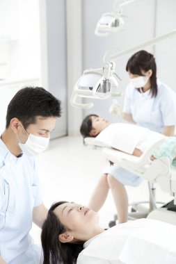 Genç kadın ve erkek dişçiler ve dişçi kliniğindeki hastalar