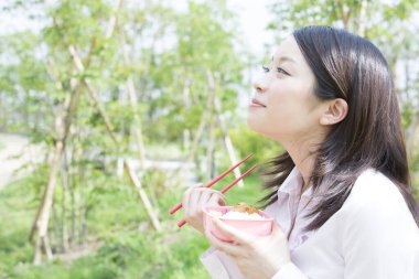 Parkta Japon yemeği yiyen bir kadın. 