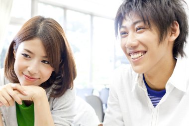 Gülümseyen adam düşünceli kadının yanında oturuyor.