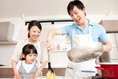 Asyalı aile mutfakta birlikte yemek pişiriyor.