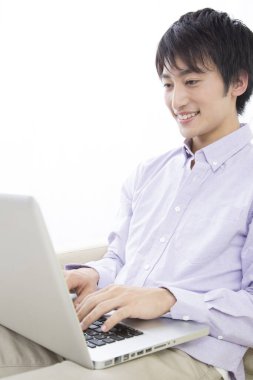 gülümseyen Asyalı genç iş adamı dizüstü bilgisayarla çalışıyor