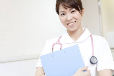 Asyalı, üniformalı, panolu bir kadın doktor.