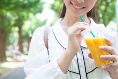 Kadın parkta meyve suyu içiyor. 