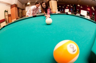 Genç çift bilardo oynuyor.