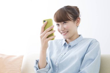 Evde akıllı telefon kullanan genç bir kadın.