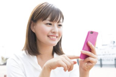 Genç Japon kadın dışarıda akıllı telefon kullanıyor.