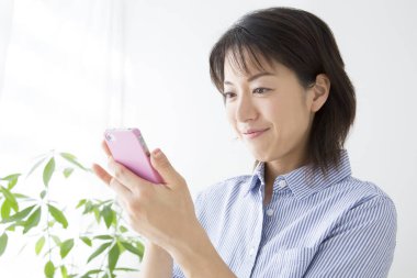 Gülümseyen ve elinde akıllı telefon tutan bir kadın.