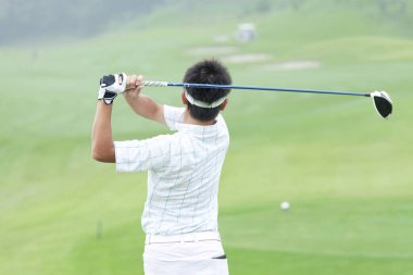 Golf oyuncusu golf sopasıyla atış yapıyor.