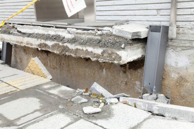 Hasarlı beton kaldırım. Kırık yapının altındaki toprağı ortaya çıkarıyor.