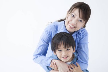 Stüdyoda poz veren Asyalı genç anne ve tatlı oğlunun portresi.