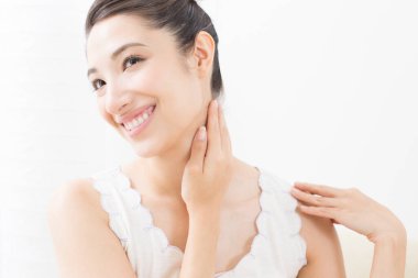 Cilt bakımı konsepti olan Asyalı bir kadın, vücuduna krem sürüyor, masaj yapıyor.