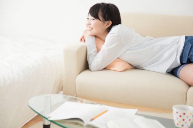 Japon kadın evdeki kanepede uzanıyor. 