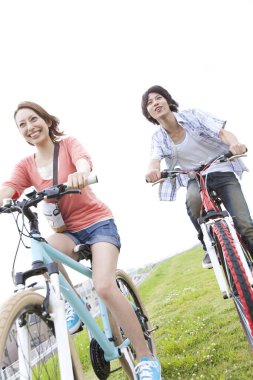 Yaz parkında bisiklet süren genç bir çift. Sağlıklı Yaşam Tarzı Konsepti.