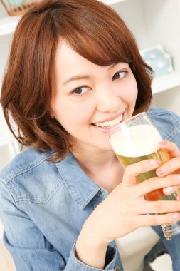 Neşeli Japon kadın evde bira içiyor.