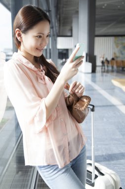 Havaalanı terminalinde akıllı telefonunu kullanan güzel bir Japon kadın.