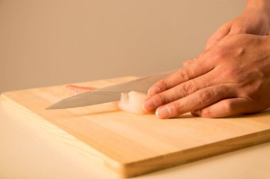 Adamın elleri bir parça taze balık kesti.