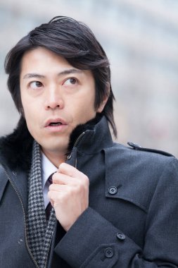 Sokakta kışın giyinmiş Asyalı bir adam. 