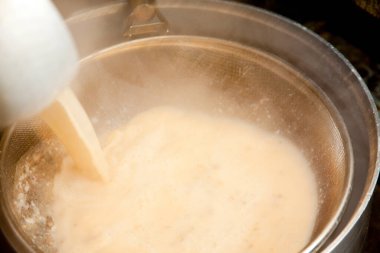 Sıcak sütü kızgın metal tencereye dök.