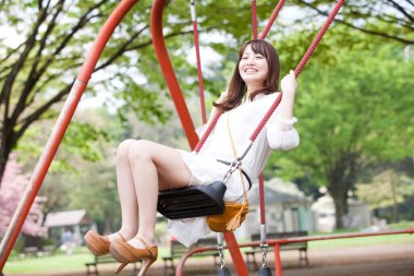 Kadın parkta salıncakta sallanıyor.