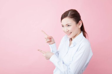 Pembe arka planda parmaklarını gösteren Asyalı genç bir kadının portresi 