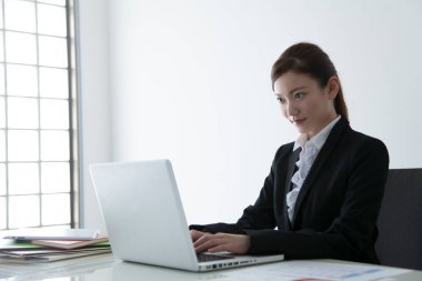 Dizüstü bilgisayar kullanan kendine güvenen Japon iş kadını.