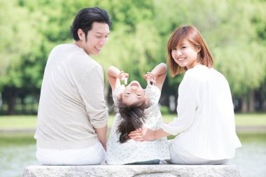 Mutlu Japon ailesinin portresi yaz parkında dinleniyor.