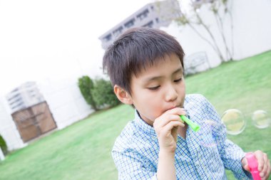 Parkta baloncuk çıkaran genç bir çocuk.