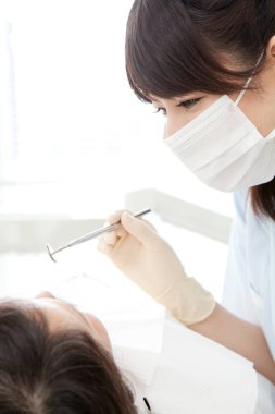 Dişlerini bir dişçi muayene ettiren bir kadın.