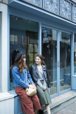 İki Asyalı genç kadın şehir sokaklarında poz veriyor.