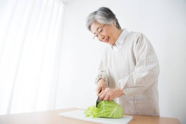 Kesme tahtasıyla lahana kesen yaşlı bir kadın.