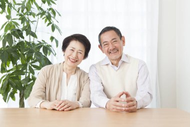 Oturma odasında oturan yaşlı Asyalı çiftin portresi.