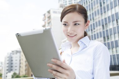 Sokakta dijital tablet kullanan Asyalı iş kadını