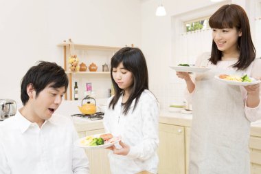 Gülümseyen aile mutfakta birlikte kahvaltı yapıyor.