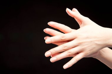 Siyah stüdyo arka planında kadın eli hareketi, yakın çekim. 