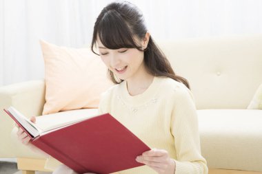 Evde kitap okuyan güzel Asyalı kadın