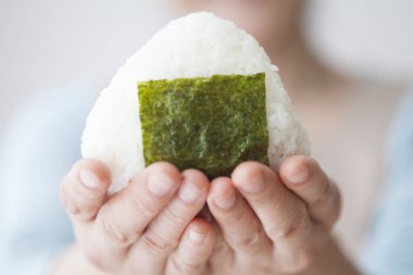 Asyalı kadın pirinçli onigiri yapıyor.