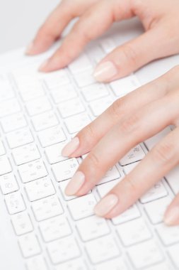 Kadın elleri beyaz klavyede, yakın plan.