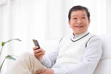 Evde akıllı telefon kullanan kıdemli bir adam.