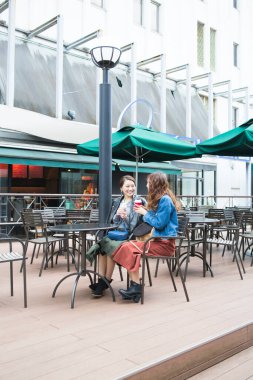 İki Asyalı bayan arkadaş sokak kafesinde oturuyor.