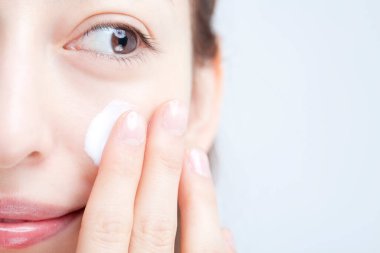 Makyaj yapan güzel genç bir kadın, beyaz arka planda yakın plan portresi