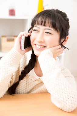 Güzel Asyalı genç bir kadın telefonda konuşuyor.