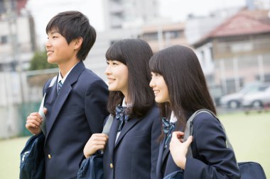 Okulda dışarıda dikilen bir grup öğrenci üniforma giyiyor. 